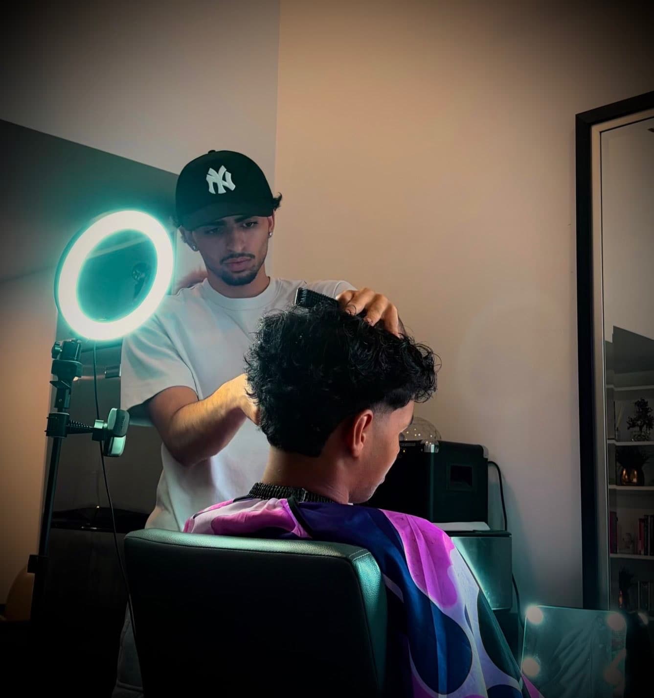 AP, owner and barber at APCUTZ, mid-cut under the ring light
